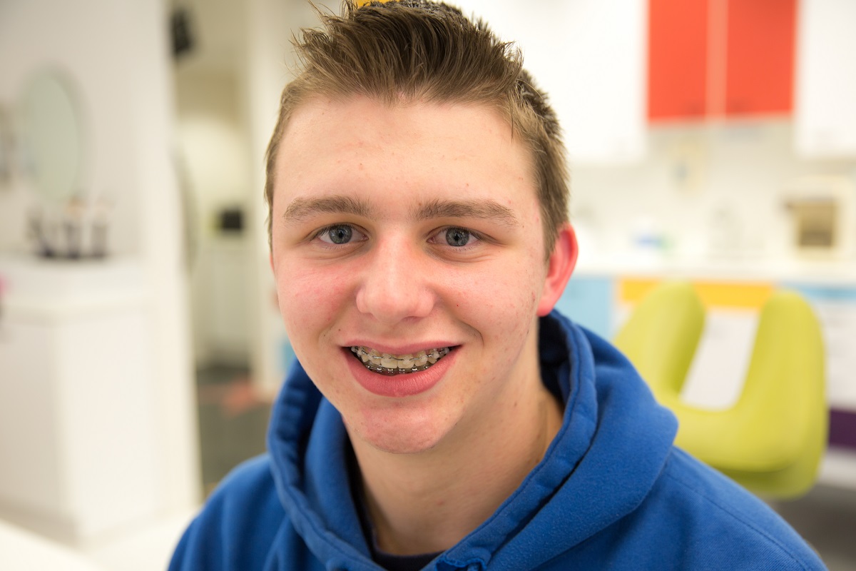 A teenage boy, smiling with his braces, highlighting the importance post-treatment care.