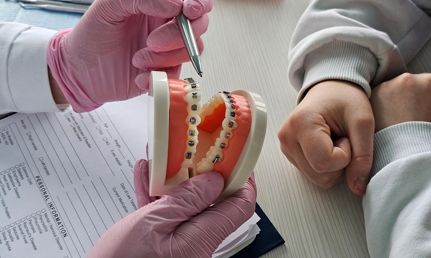 Orthodontist showing a bite model with braces to a patient during an appointment