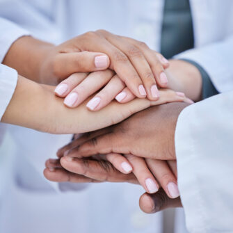 Image of orthodontists hands stacked on top of one another to show support to patients of mail-order treatment.