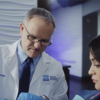 An orthodontist conducting an in-person consultation, thoroughly examining a patient's teeth, jaws, bite, and facial structure to identify orthodontic issues.