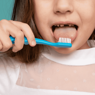 Child brushing her teeth, demonstrating when it may be appropriate to start phase 1 treatment, with a mixed dentition.