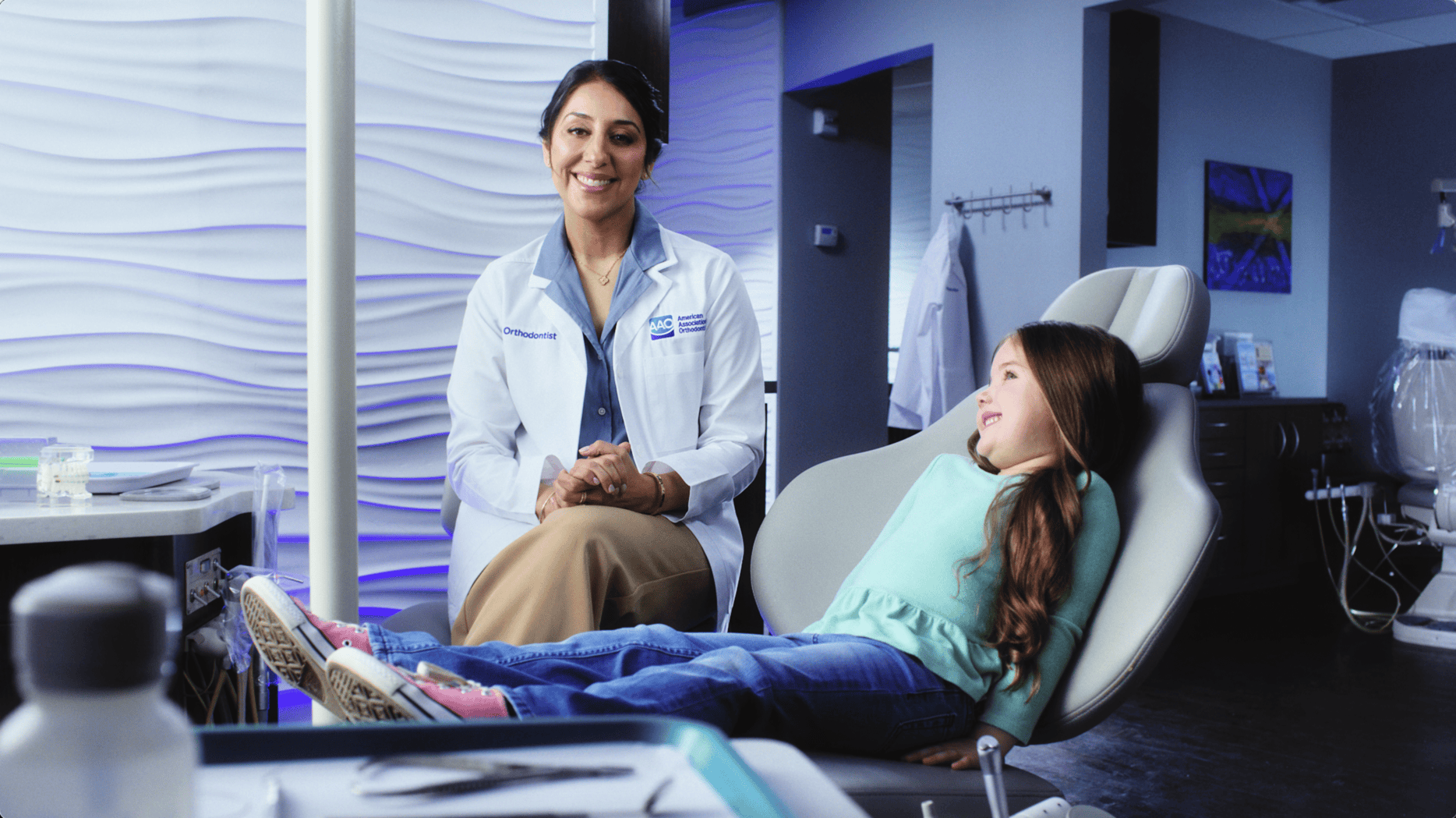 AAO orthodontist smiling next to child patient in an office setting
