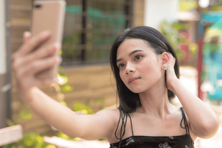 A teenage girl taking a selfie, representing Mewing, a DIY facial restructuring trend, with a reminder that tongue posture alone cannot replace proper orthodontic treatment. And there is no scientific evidence to support the Mewing claims.